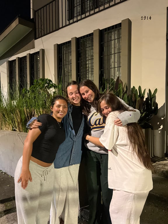 A group of four study abroad students standing together and smiling at the camera