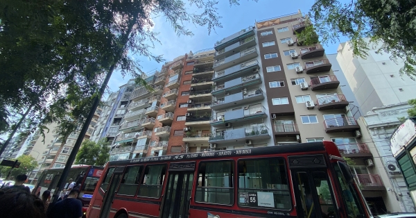 A Buenos Aires street with red buses driving past