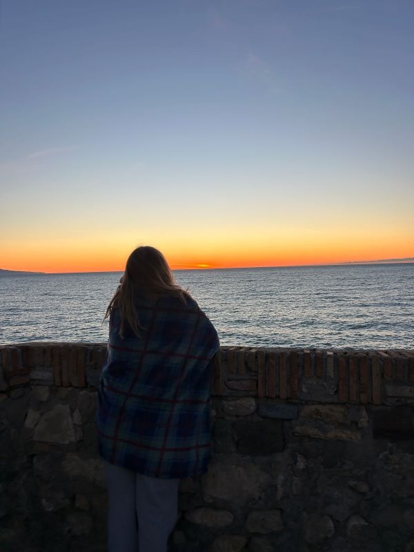 Photo of study abroad student looking at the sunrise on the coast