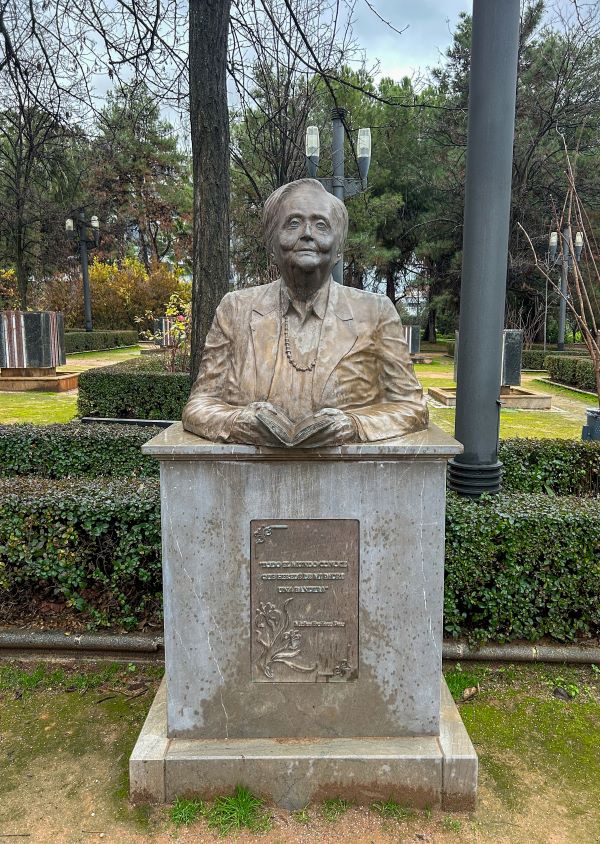 A statue in an outdoor space featuring a man holding a book