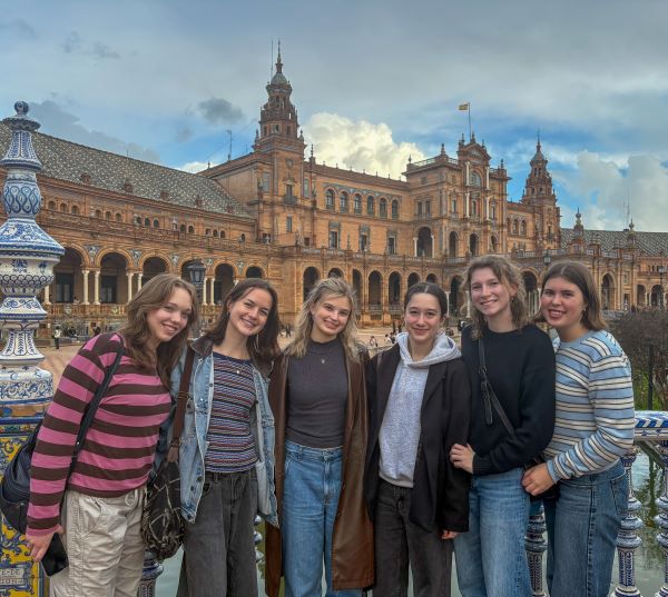 A group of study abroad students smiling at the camera in front of a large ornate building