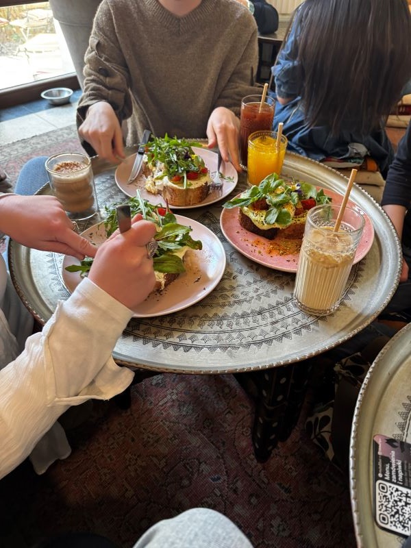Several people seen from the neck down seated at a restaurant table laden with plates of food