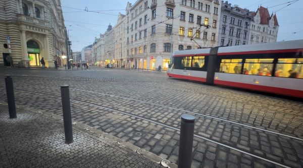 A white and red tram driving forward on a cobblestone city street
