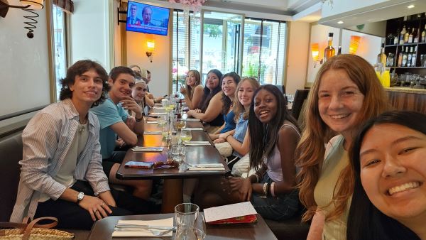 A large group of study abroad students taking a selfie while sitting at a restaurant table indoors