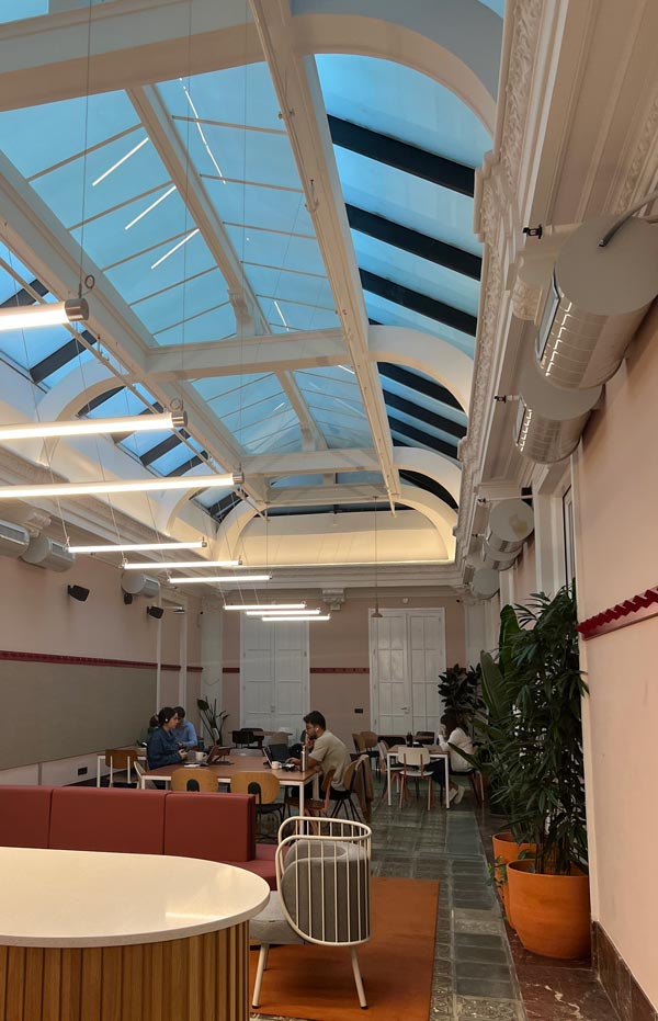 A room with a glass roof and a group of people sitting at tables