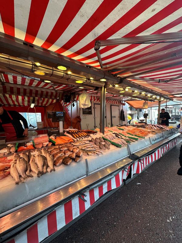 A counter of fish on ice in a covered outdoor market stall