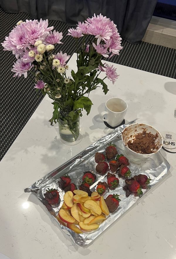 Sliced apples and chocolate covered strawberries with vase of flowers