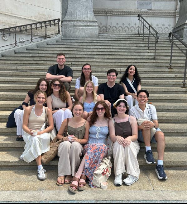 A group of study abroad students sitting on outdoor stairs and smiling at the camera