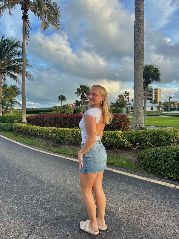 A study abroad student standing outdoors and turned to the side while smiling at the camera