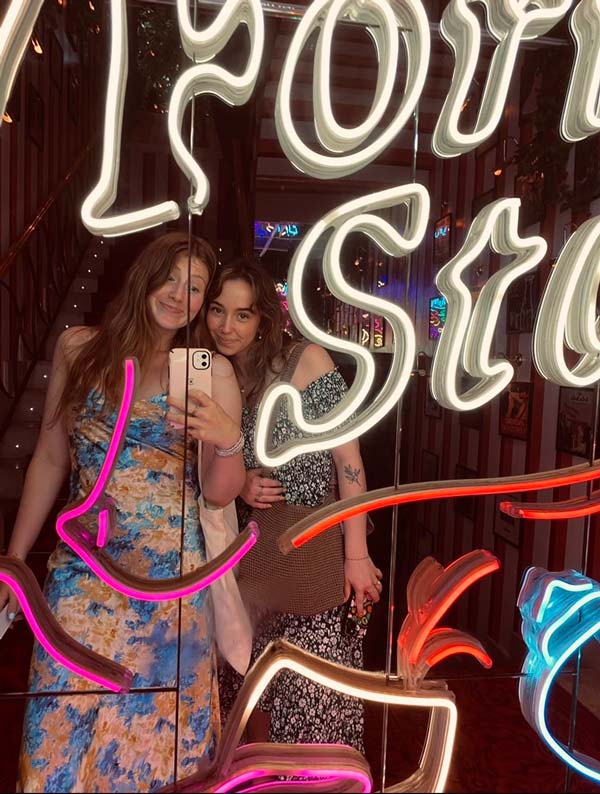 2 study abroad students taking a selfie in front of a neon sign