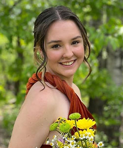 A person smiling with a bouquet of flowers
