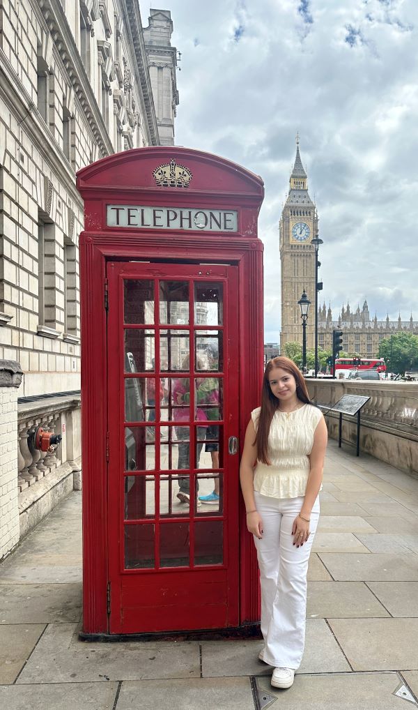 Study abroad student posing for photo with red telephone booth