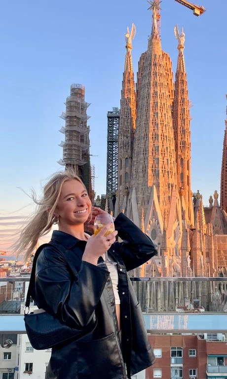 a person holding a drink in front of a tall building