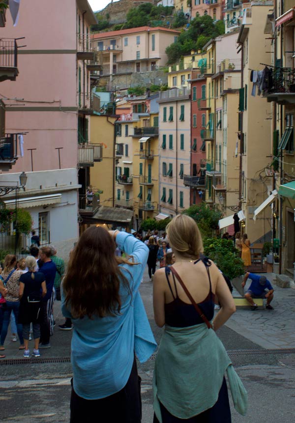 two people walk downhill in a busy Italian street