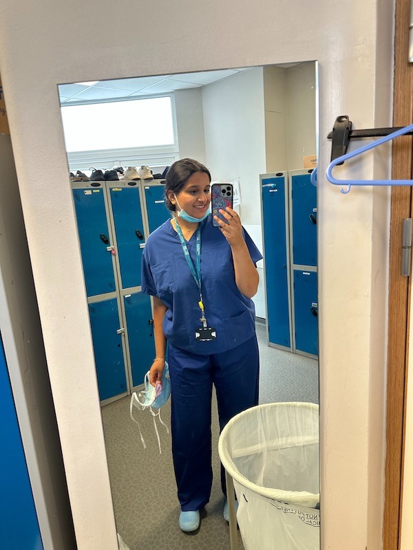 person in scrubs taking a mirror selfie
