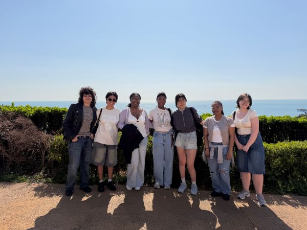 Seven study abroad students standing outdoors under a sunny sky and smiling at the camera