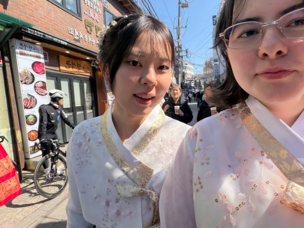 Two study abroad students taking a selfie while wearing intricately embroidered white garments while gold and pink trimmings