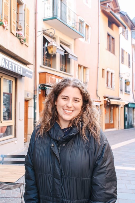 A person smiling in front of European buildings