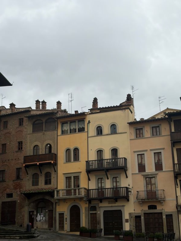Six tall thin stone buildings in various shades of beige and orange stood next to each other on a city street