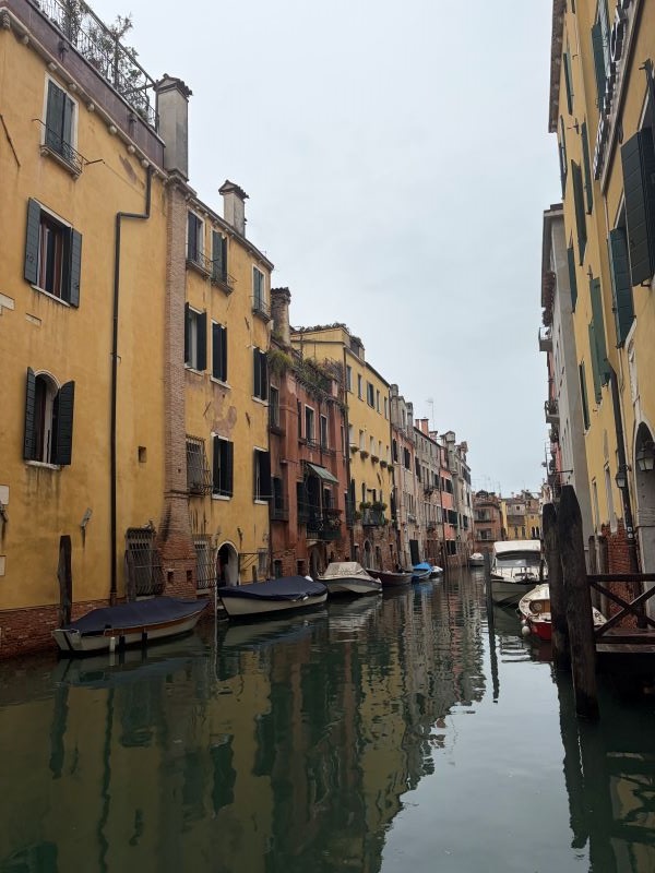A body of water surrounded on either side by tall thin stone city buildings