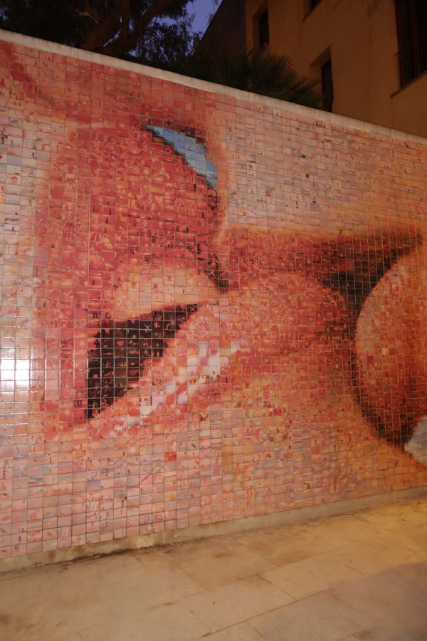 A large mural on a wall showing a close up of two light-skinned mouths kissing
