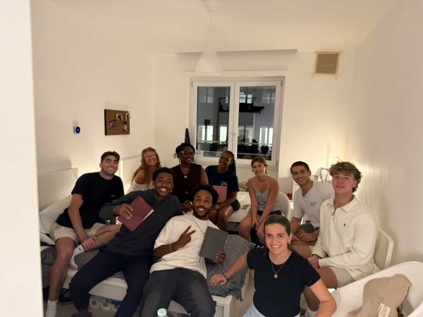 A group of study abroad students sitting in an indoor space and smiling at the camera