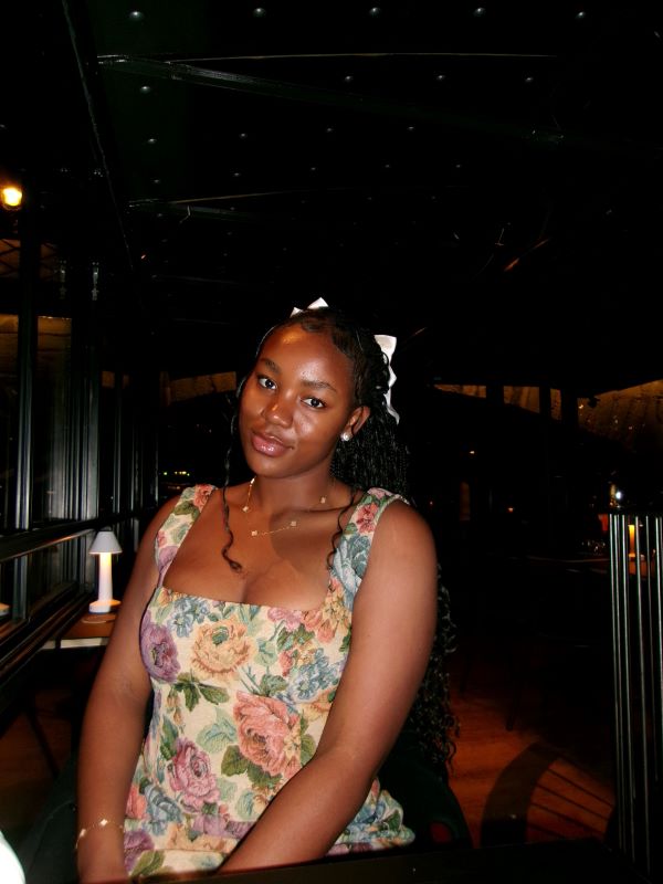 A study abroad student wearing a floral-patterned dress while sitting indoors and smiling at the camera