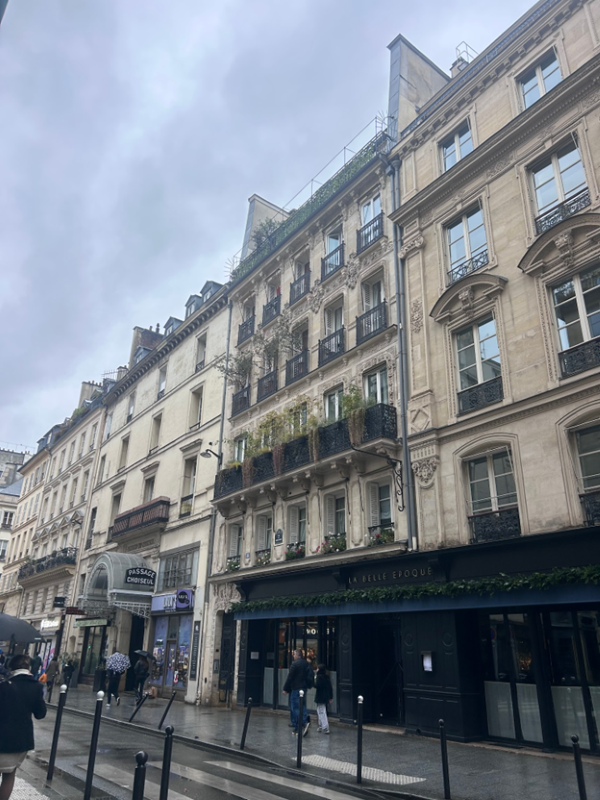 People walking a long a city street full of tall sand-colored ornately decorated buildings