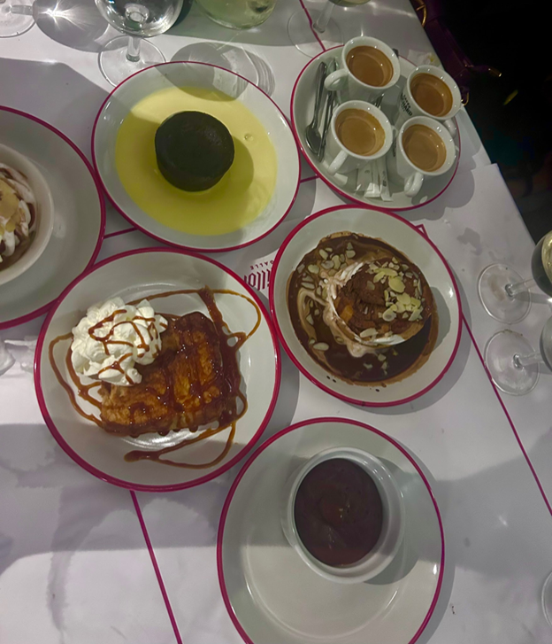 Several plates of various types of desserts sitting on a white restaurant table as seen from above
