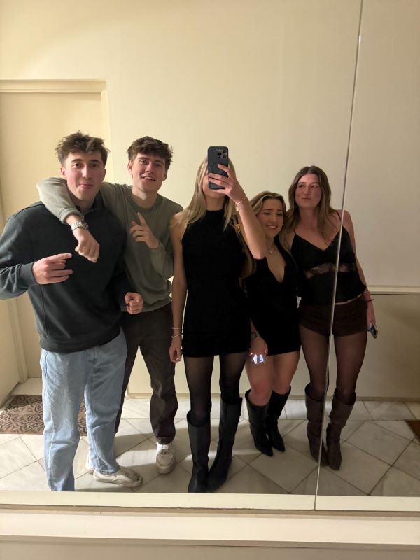 A group of five study abroad students standing and taking a selfie in a mirror in an indoor space