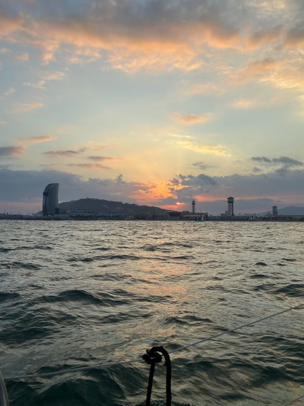 A large body of water seen during low sunlight with a mountain and city buildings in the distance