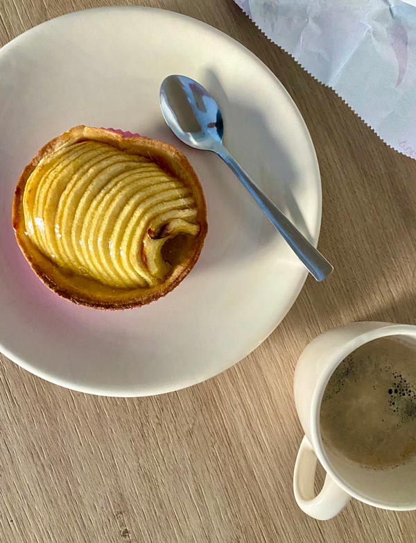 A pastry sitting on a plate next to a mug of liquid