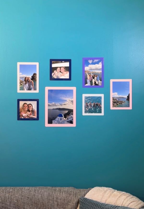 An indoor wall painted blue and featuring seven photos with colorful frames