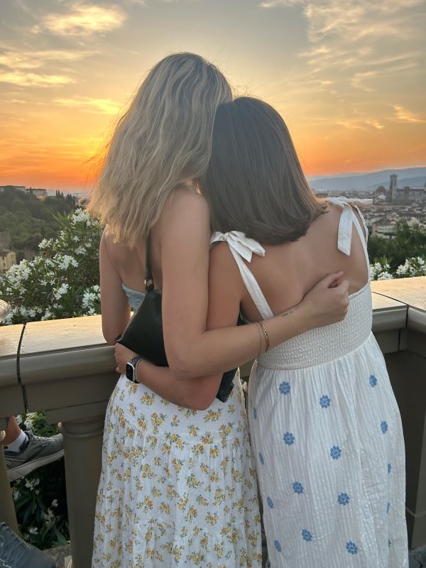 Two study abroad students embracing while looking at sunset view