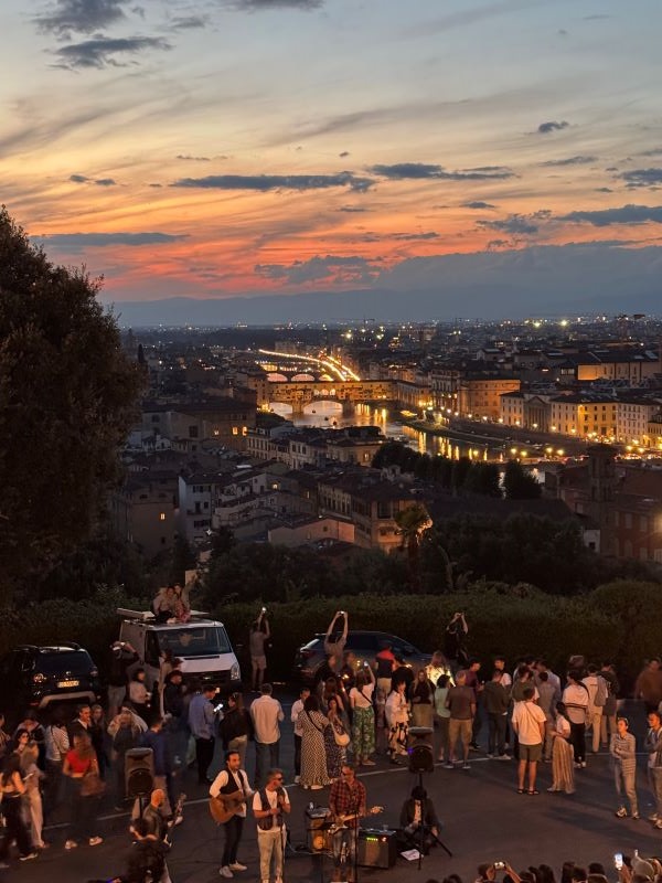People gathered around street performers with view of Florence