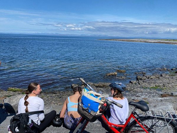 A group of study abroad students sitting on a rocky beach with bikes