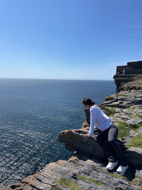 A person sitting on a rock overlooking the ocean