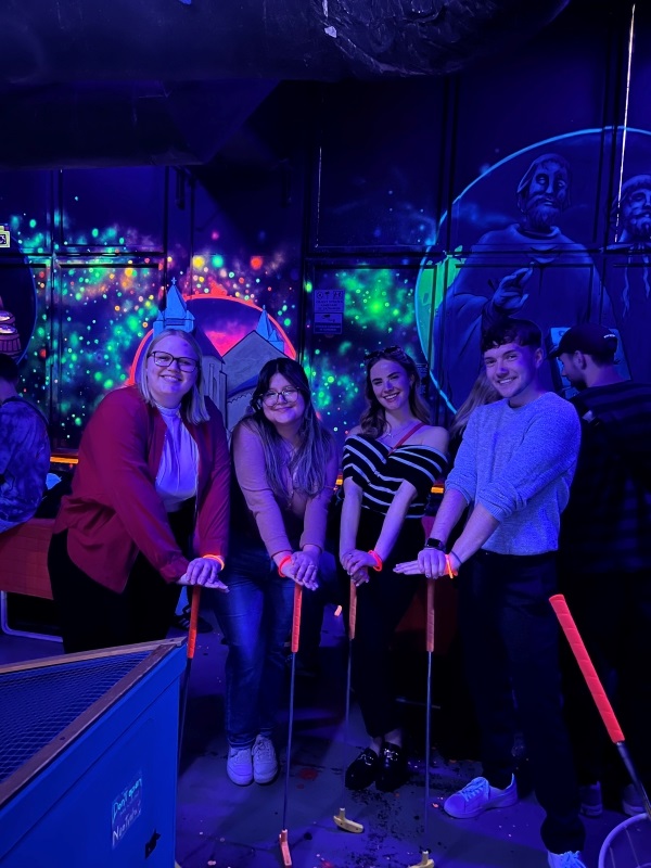 Four study abroad students posing for photo while mini golfing