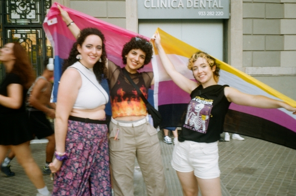 Three locals posing for a photo holding their queer flags