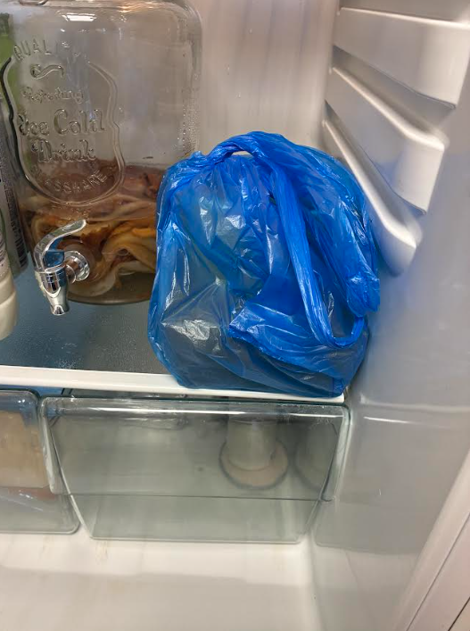 The interior of a refrigerator featuring food wrapped in a blue plastic bag