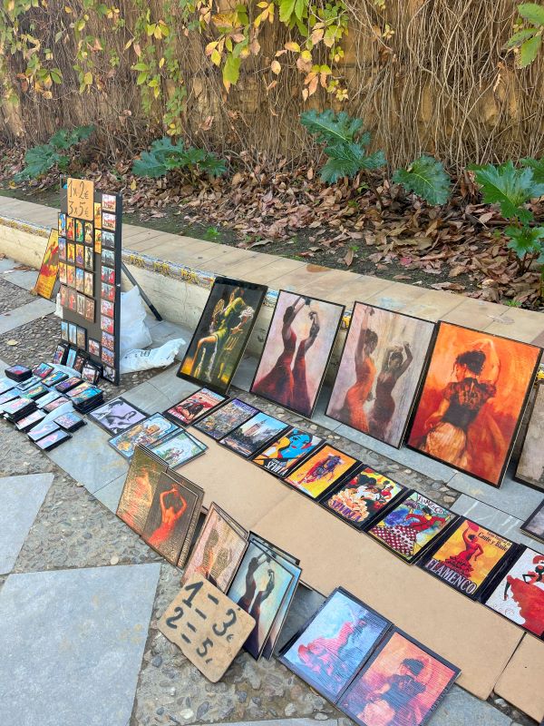 Displayed paintings of flamenco dancers on sidewalk