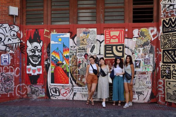 Four study abroad students posing for photo in front of graphiti wall