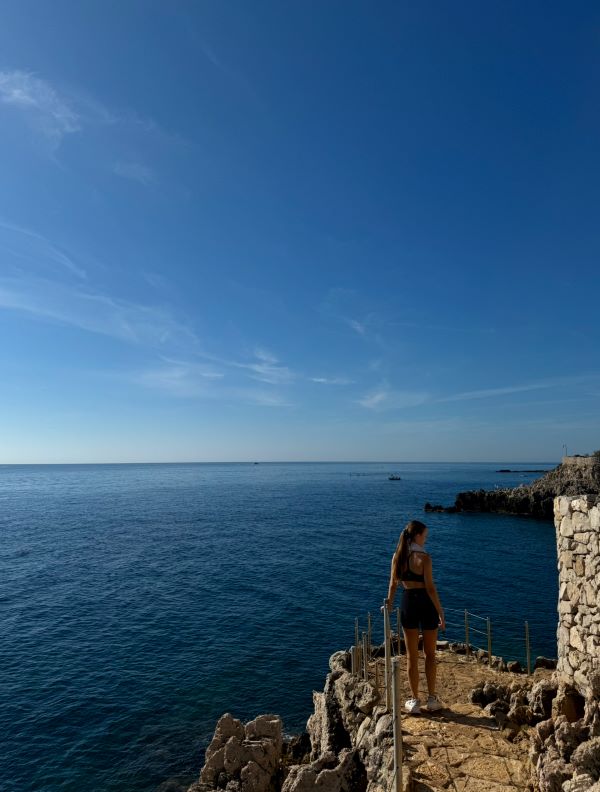 A study abroad student as seen from behind standing overlooking a large body of water