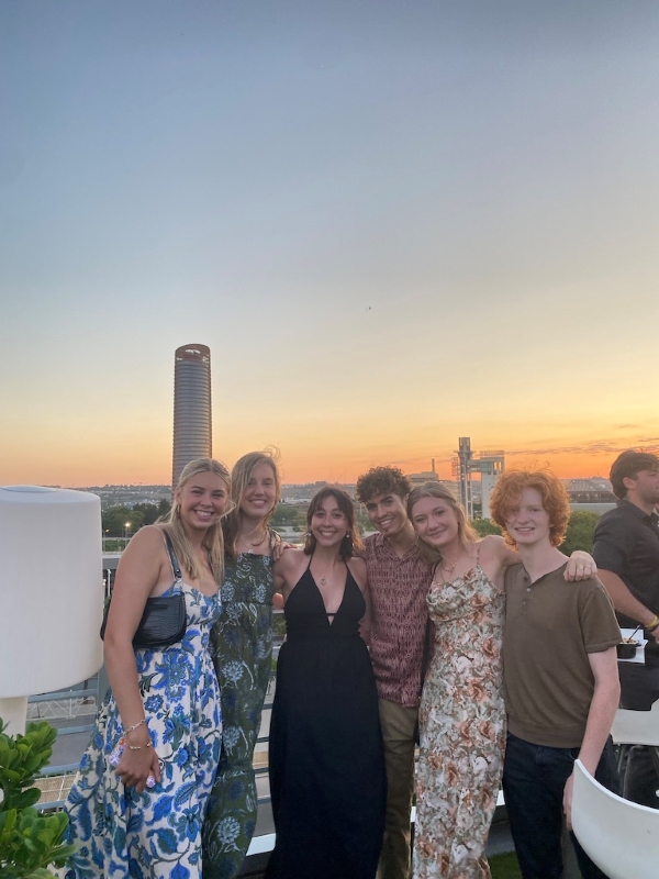 six study abroad students posing for photo on roof during sunset