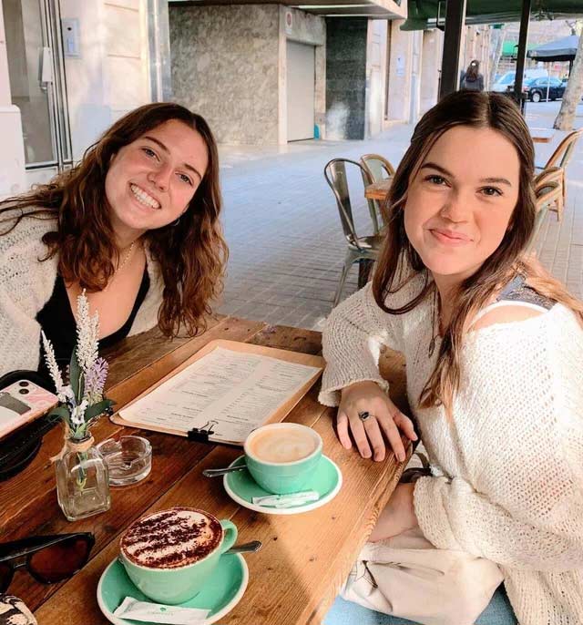 Two friends smiling with two coffees on the table at a cafe