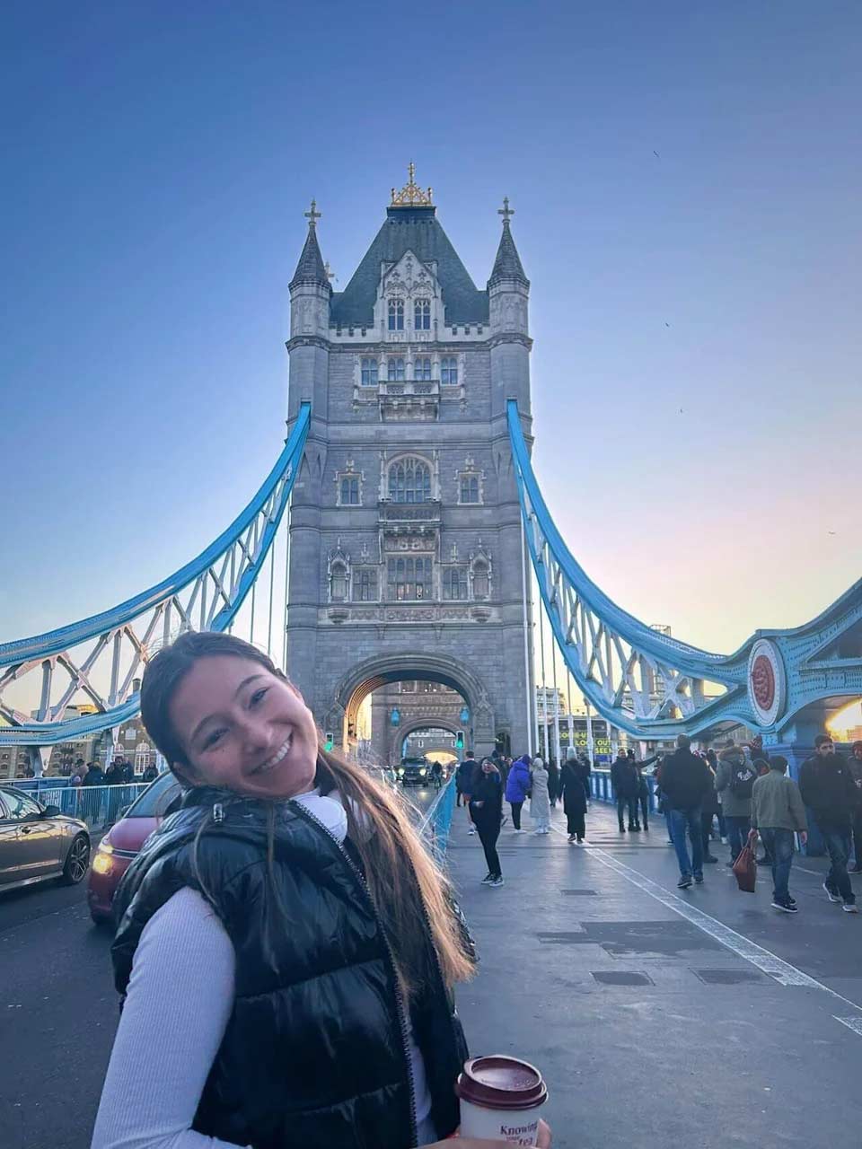 A student smiling in front of the Tower Bridge