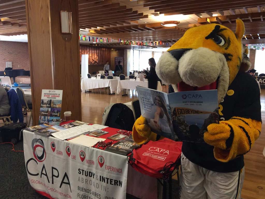 university mascot reading a CAPA brochure next to our booth at a study abroad fair on campus