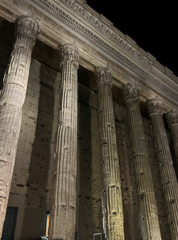 A large stone building with tall columns seen from below seen during nighttime