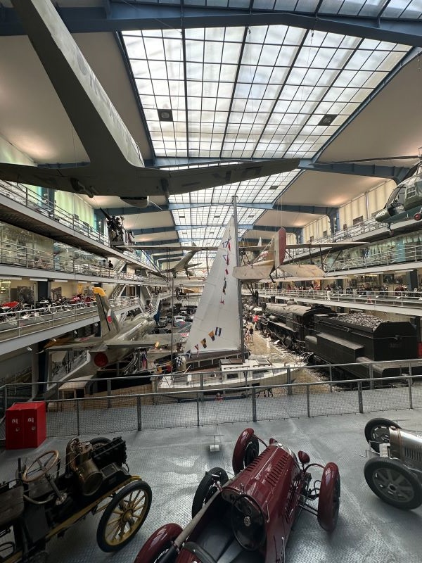 The interior of a large building featuring a large number of cars and small ships on display