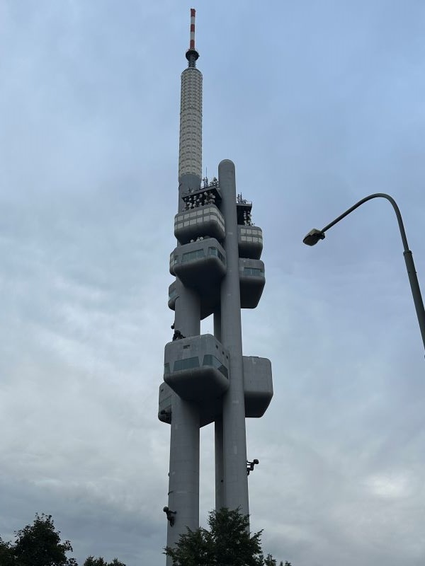 A large tall gray tower as seen from below against a cloudy blue sky